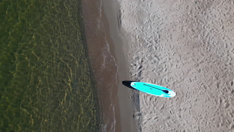 Sup-board-Paddleboard-on-sunny-beach-next-to-ocean,-Bulgaria,-top-down-aerial-view