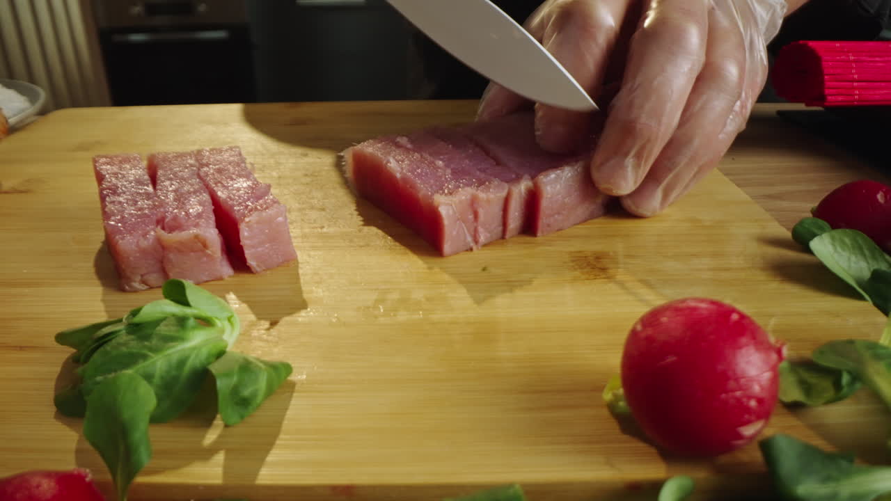 Chef Cutting Raw Tuna on a Wooden Board for Sushi Preparation