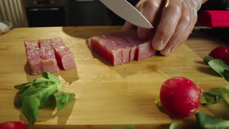 chef cutting raw tuna on a wooden board for sushi preparation