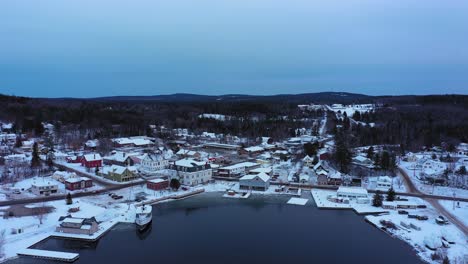 imágenes aéreas volando alto sobre el lago moosehead y un centro cubierto de nieve en greenville, maine