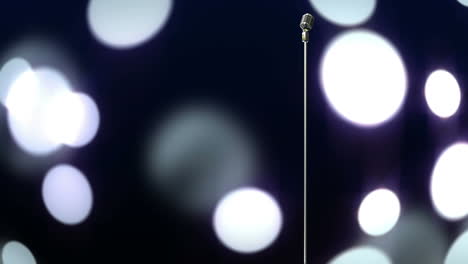 micrófono metálico retro contra manchas de luz contra un fondo negro