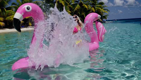 two women having fun at tropical beach with flamingo inflatable