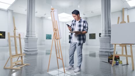 cuerpo lleno de artista masculino asiático que encuentra inspiración en el teléfono inteligente mientras pinta en lienzo con pinturas al óleo y pincel en la galería