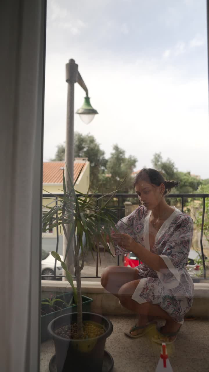 Woman Caring for Plants on Balcony