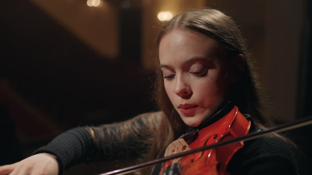young beautiful female violinist in symphonic orchestra woman is playing violin in music hall