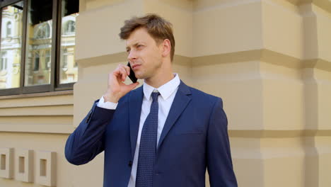 focused business man talking mobile phone outdoors. confident businessman