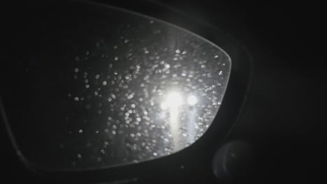 the headlights of a car in the column on the rain-tipped road seen in the rear-view mirror splashed with splashes of water 357