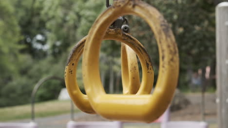 slow motion medium shot of yellow playground rings swinging