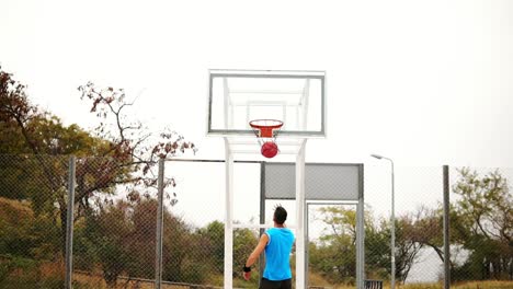 back view of young man playing basketball and throwing a ball to the basket successfully. slow motion shot
