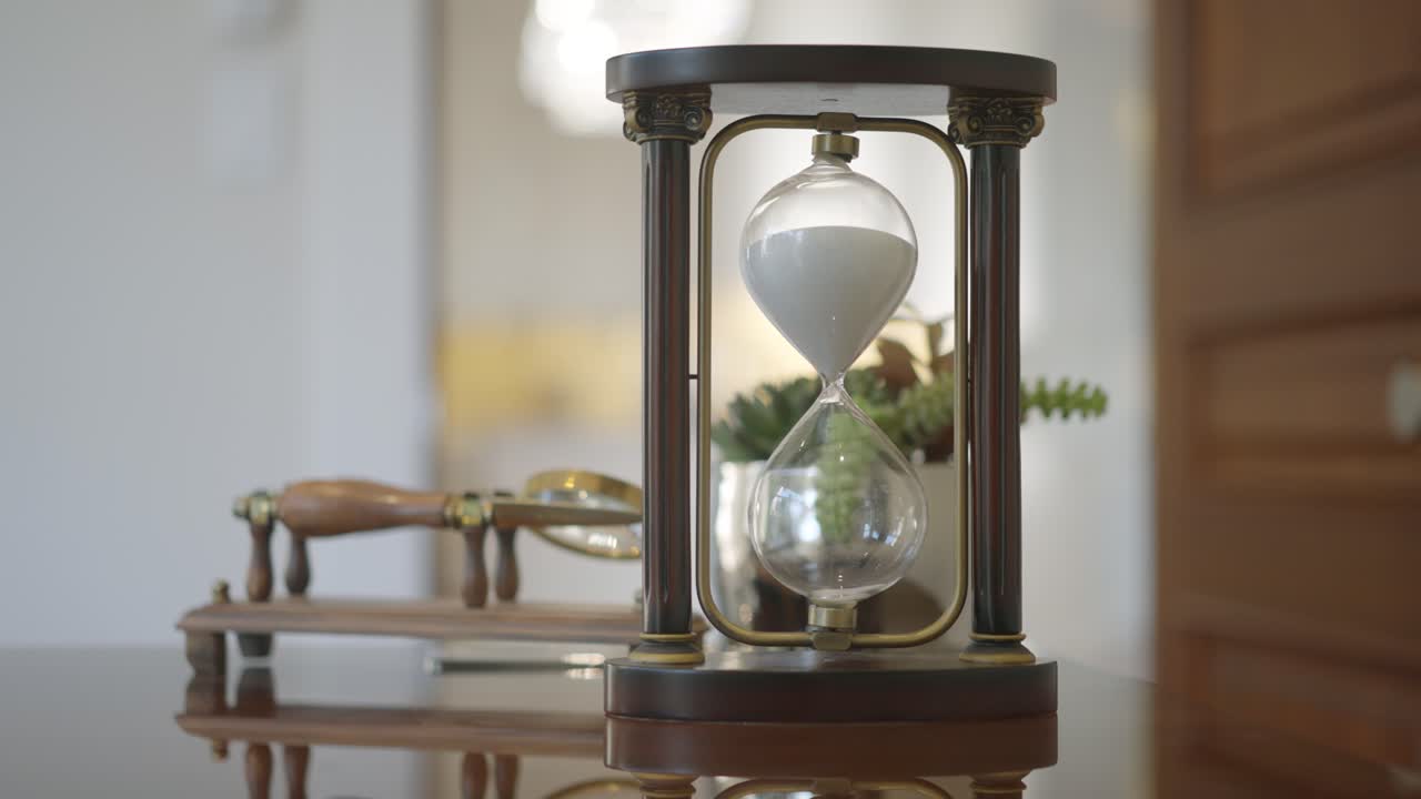 A close up shot of an elegent luxurious hourglass on top of a hardwood luxury desk
