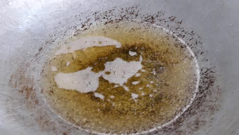 adding mashed garlic, coriander root and pepper to boiling oil, close up