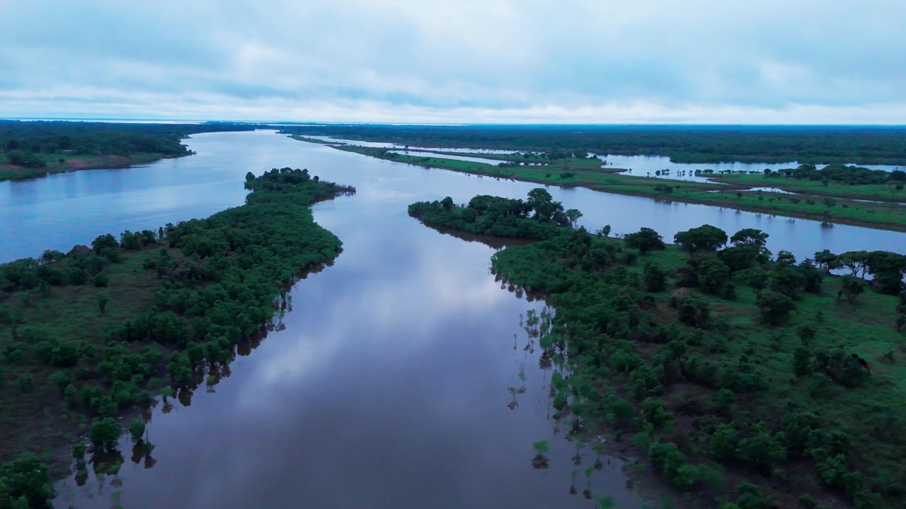 Aerial panorama of the Amazon River flowing through tropical rainforest in the Brazilian Amazon during the evening, showcasing winding waterways, lush vegetation and cloud reflections