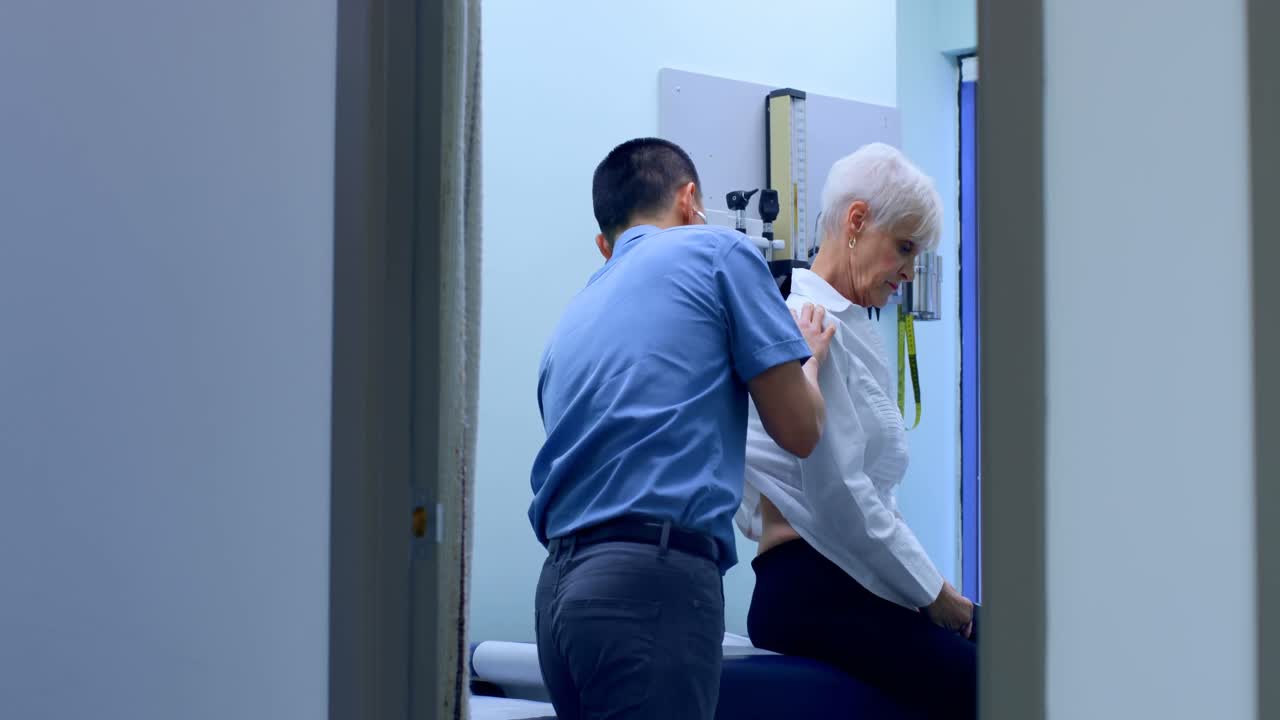 joven médico asiático examinando a un paciente anciano en la clínica 4k