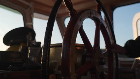 a person's hand on a ship's wooden steering wheel