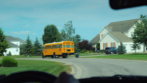 view from the window of the car which goes after the school yellow school bus in the us suburb