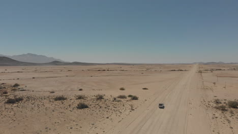 right panning shot over vehicle driving alone on desert road