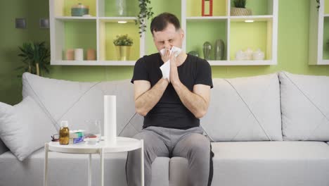 cold man sneezes at home, has a runny nose. flu.