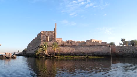 ancient temple of philae from a boat during sunrise in aswan, egypt