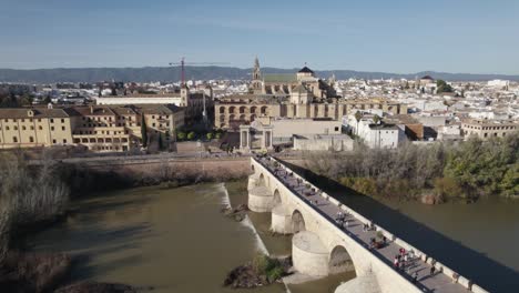 people walking on cordoba roman bridge, spain. aerial sideways