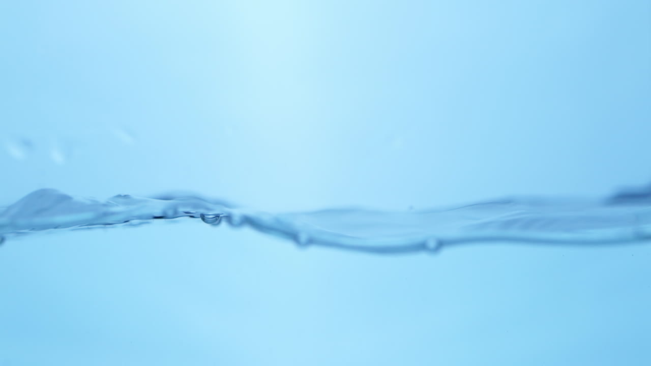 Elegant slow-motion close-up of blue water surface, showcasing its refreshing and pure qualities, ideal for promoting hydration and wellness.