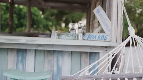 Empty-hammock,-and-glasses-and-painted-signs-on-counter-at-beach-bar,-in-slow-motion-with-copy-space