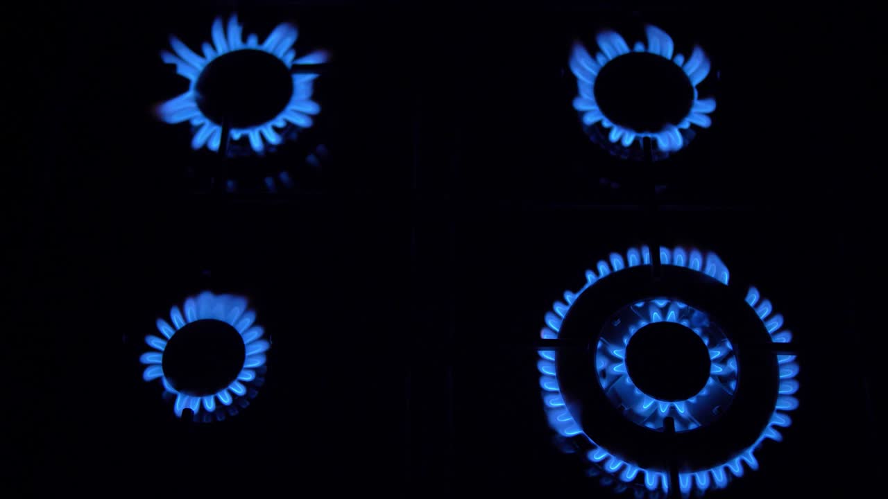 가스 스토브가 켜지고 꺼지고 파란 불꽃이 어 속에서 불타고 있습니다.