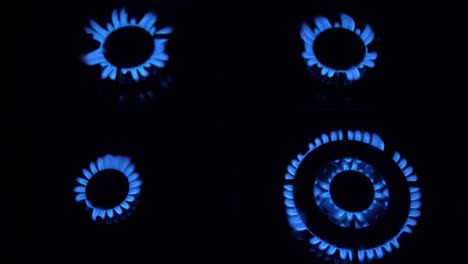 estufa de gas encendida y apagada con llamas azules fuego en la oscuridad