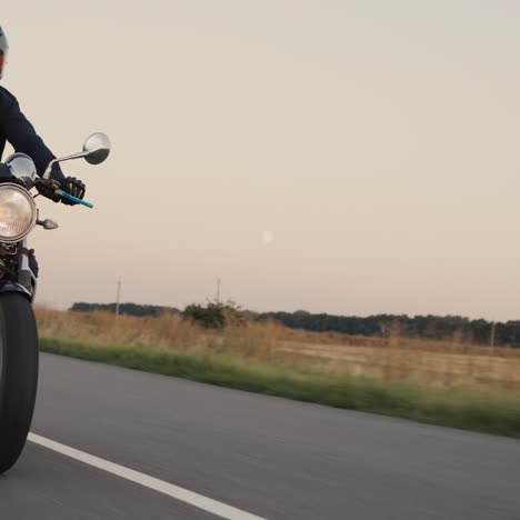 biker in dark clothes rides on picturesque rural road