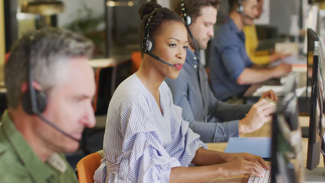 retrato de una feliz mujer de negocios afroamericana usando auriculares de teléfono y mirando a la cámara en la oficina