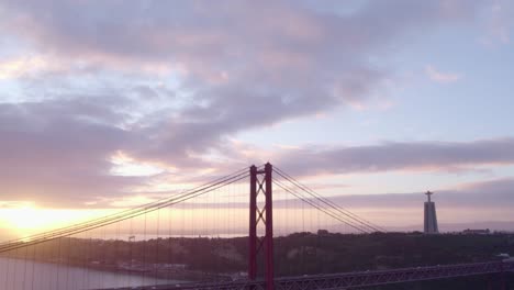 tilt down shot of ponte 25 de abril lisbon above tagus river at sunrise, aerial