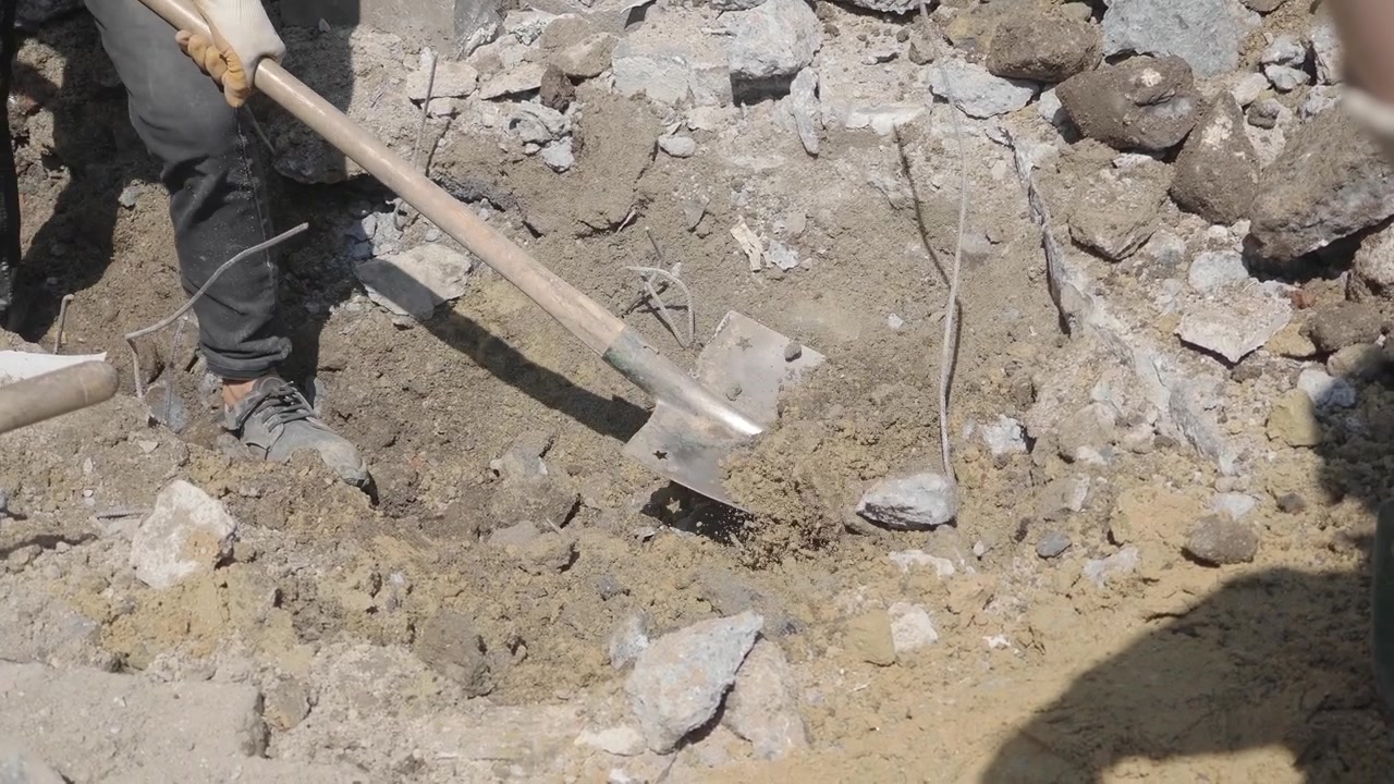 Operaio edile che pala detriti in un cantiere di demolizione