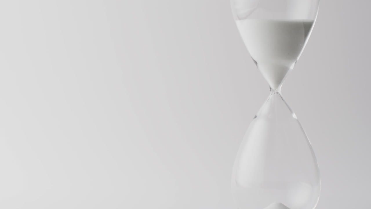 Video of hourglass with sand pouring, copy space on white background