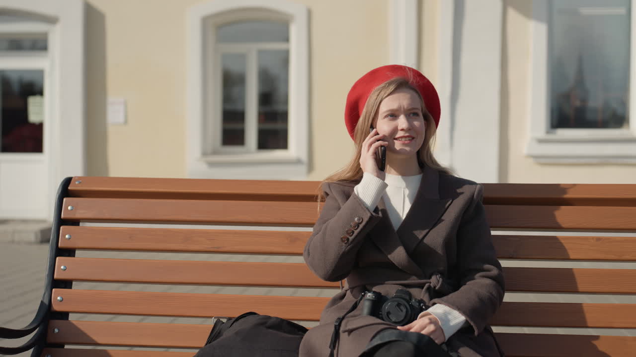 Signora che scatta foto felicemente all'aperto. Una fotografa con il basco si diverte con i servizi fotografici all'aria aperta. Una donna con la macchina fotografica e un'espressione allegra discute i suoi piani fotografici in una giornata di sole all'aperto.