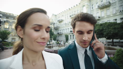 business couple walking outdoors together. handsome man talking mobile phone