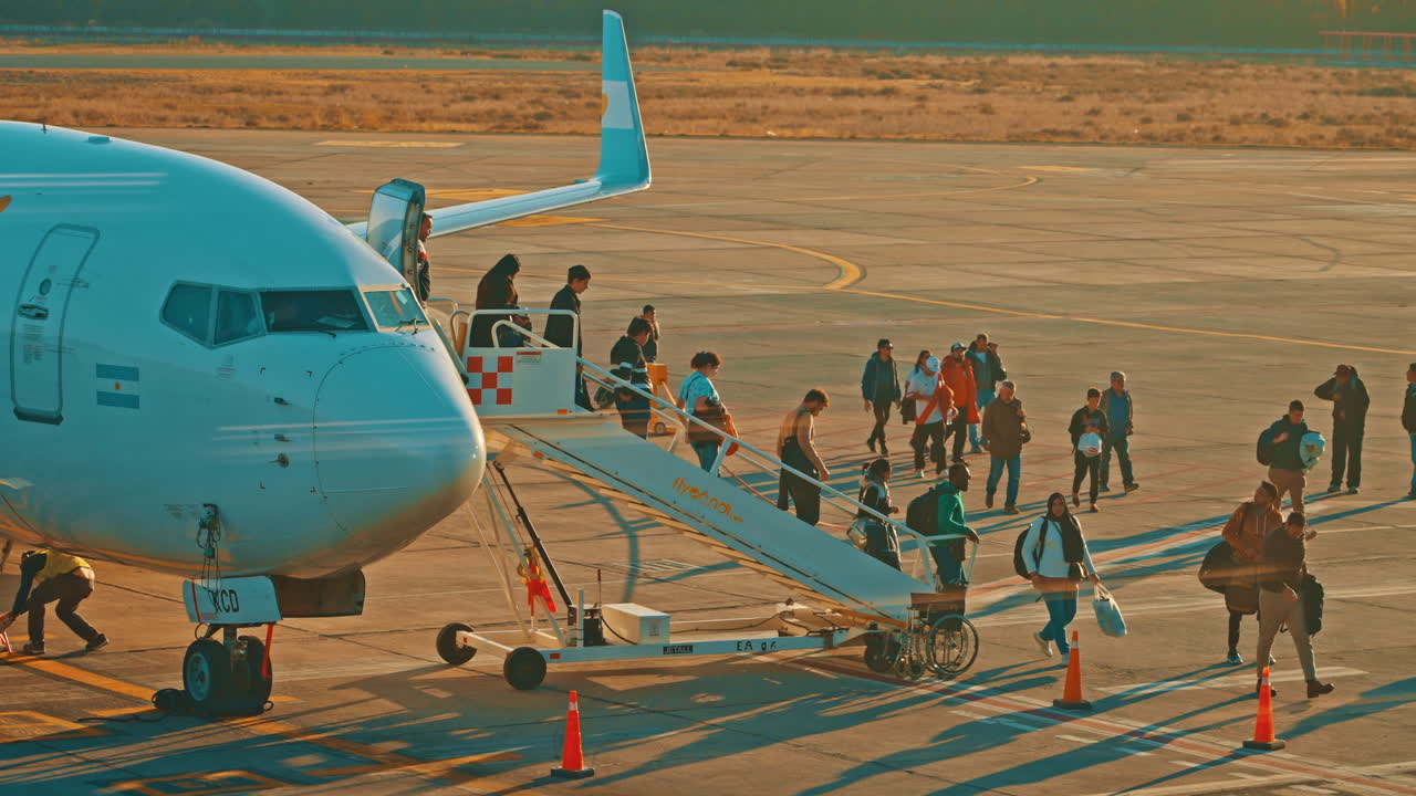 Passengers Boarding an Airplane on the Tarmac at Sunset