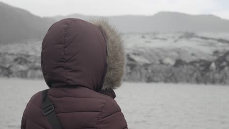 slow orbiting shot of a tourist looking out onto the melting glaciers in iceland