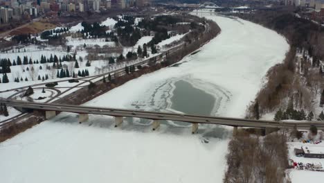 Vista-Aérea-De-Pájaro-Volar-Sobre-Groat-Rd-Nw-Puente-Cubierto-De-Nieve-Helado-Río-Saskatchewan-Norte-En-Una-Tarde-Sombría-De-Invierno-Rodeado-De-Tranquilos-Campos-De-Golf-Y-Parques-A-Cada-Lado-Edmonton-Alberta-3-7