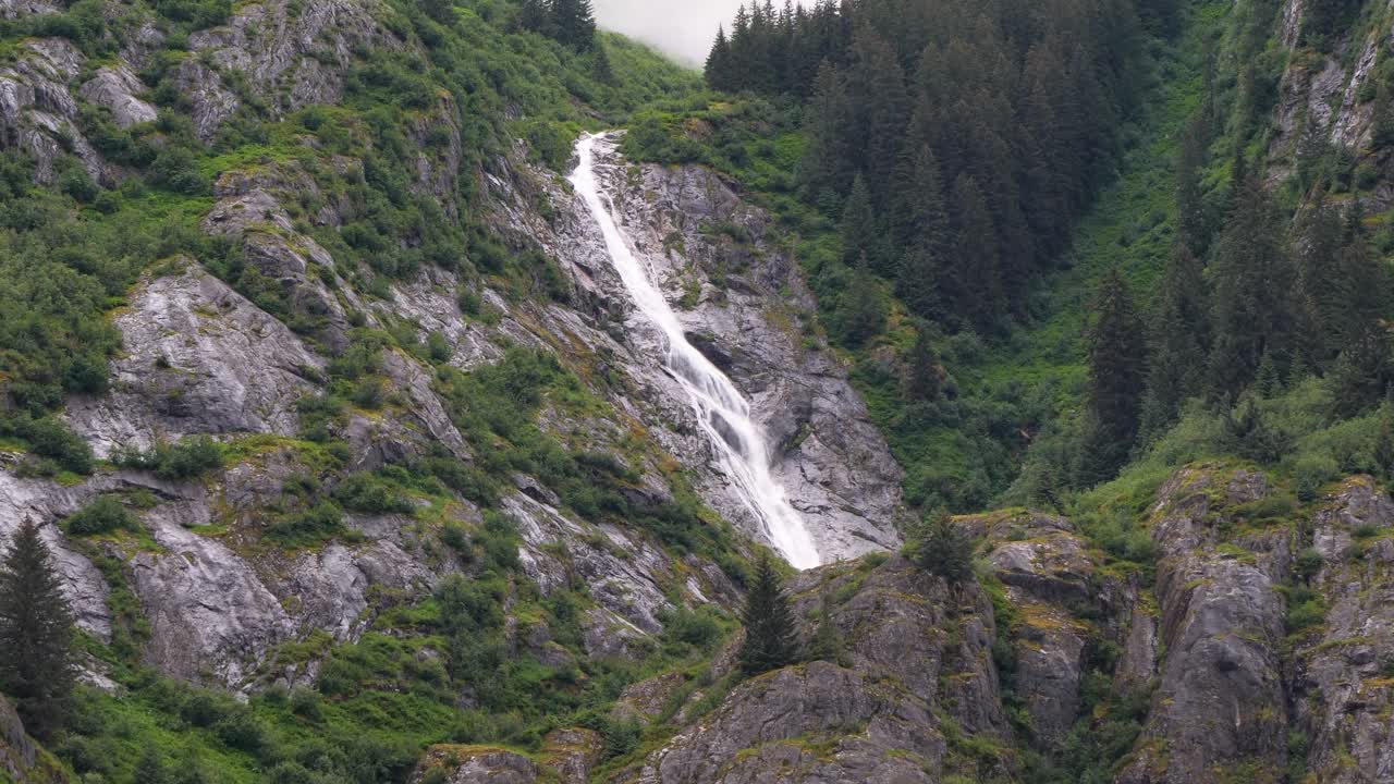 Picturesque waterfall along the granite steep wall of the mountain at Endicott Arm Fjord, Dawes Glacier, Alaska.