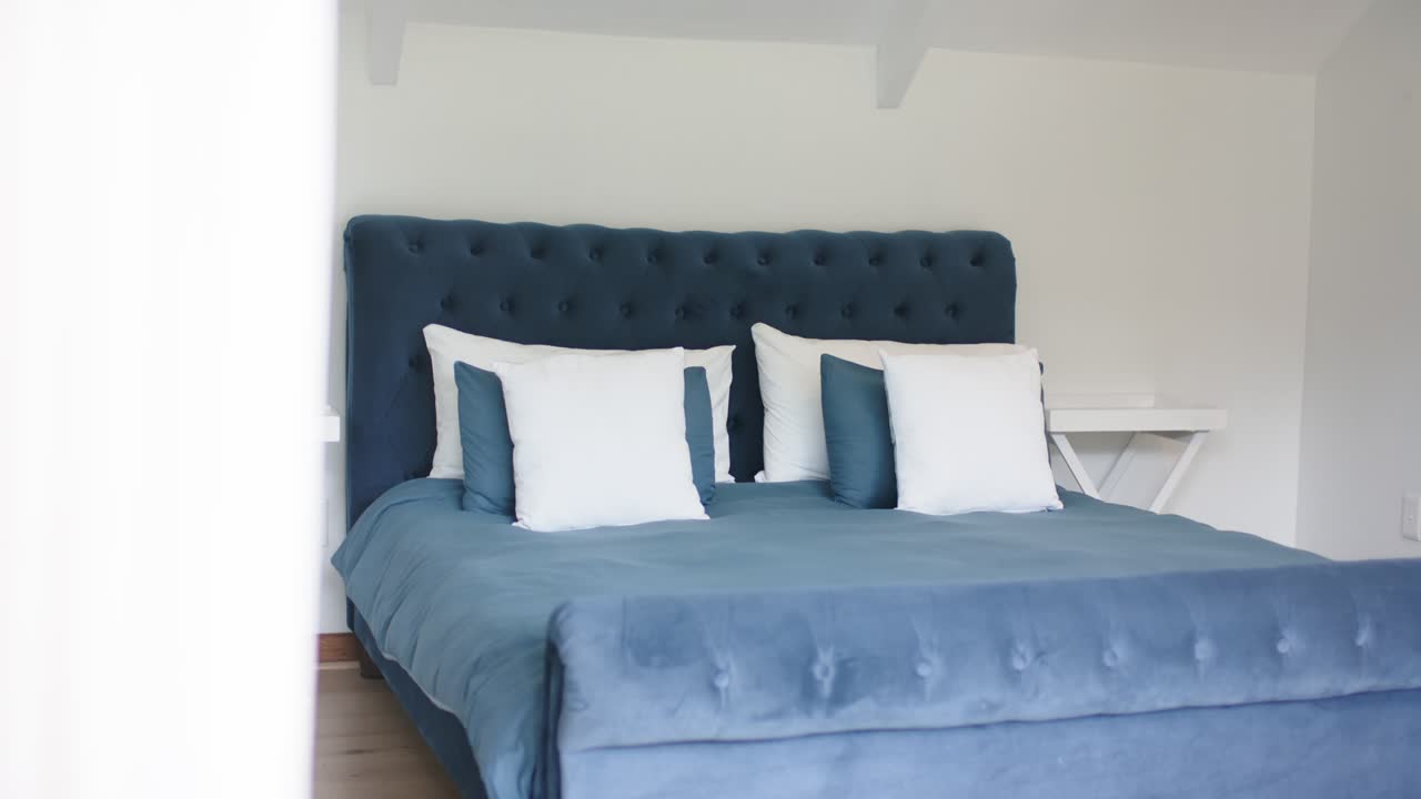 Il motore sposta il pannello della porta scorrevole, rivelando una testiera imbottita e un letto queen-size per la presentazione della stanza.