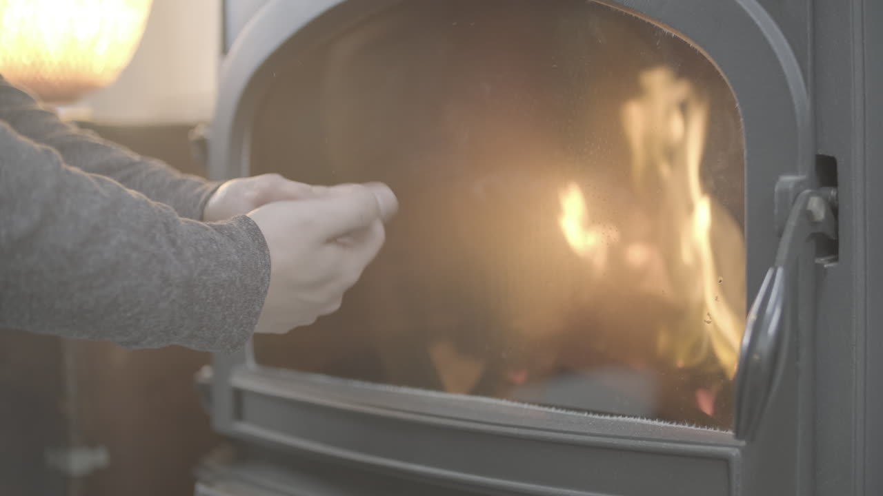 Сlose Up View Of Fireplace Indoors, Hand Puts Firewood In Fireplace. Cozy Weekend