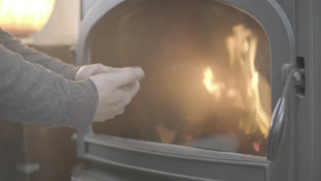 сlose up view of fireplace indoors, hand puts firewood in fireplace. cozy weekend