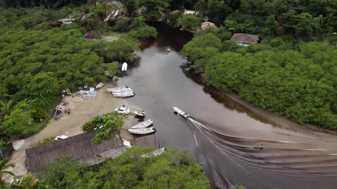 vista aérea siguiendo un estacionamiento de botes en la costa arenosa del río sahy, en el nublado brasil