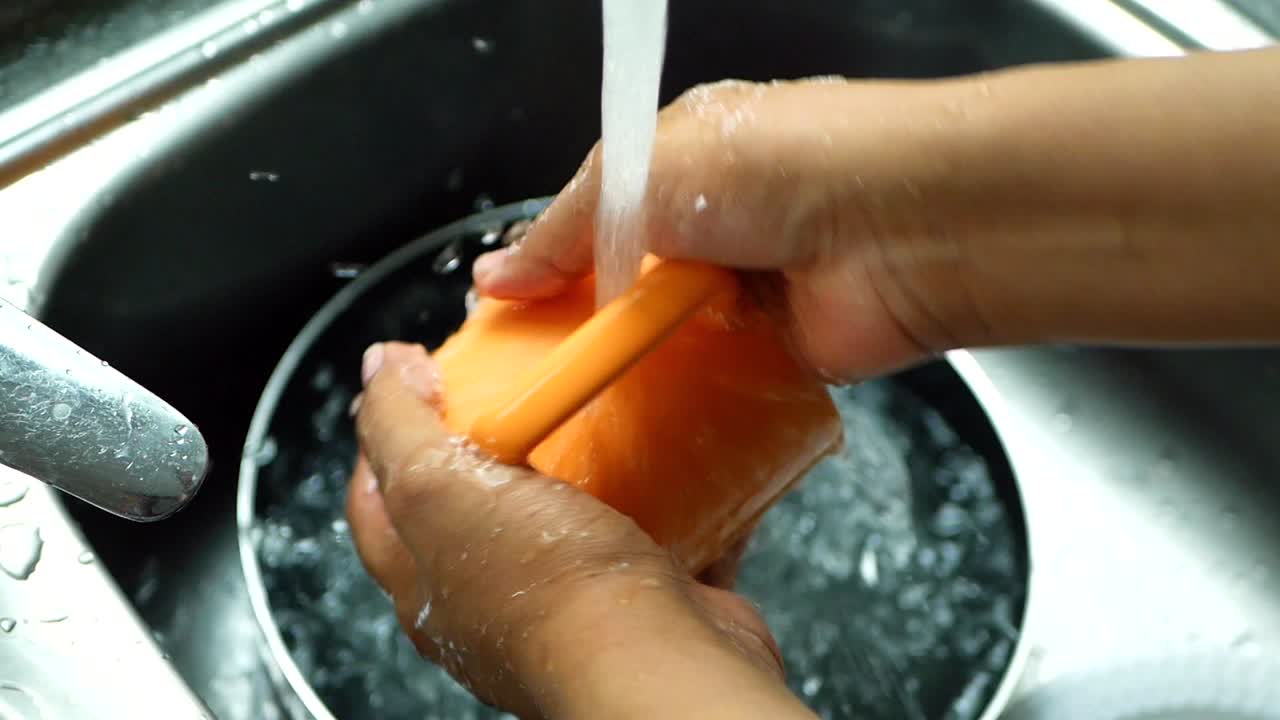 Lavando una taza naranja en el fregadero de la cocina