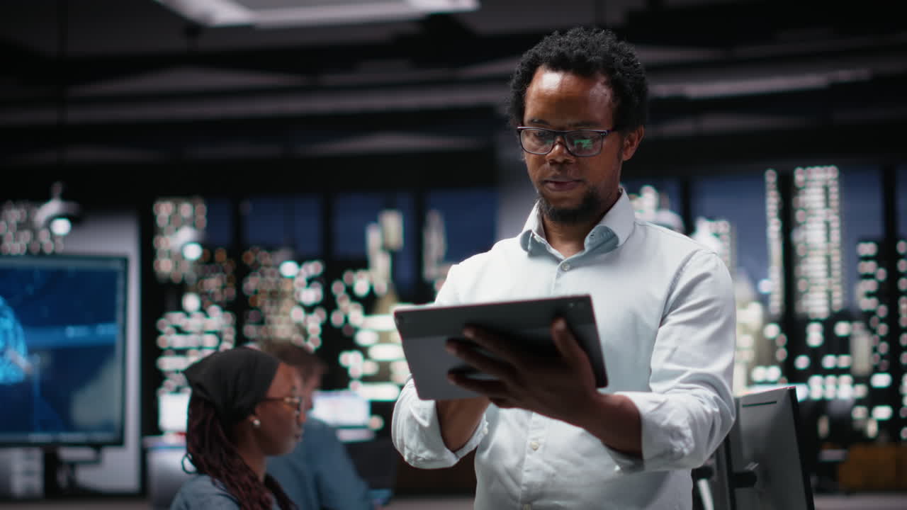 African American Man Using Digital Tablet in Modern Office at Night