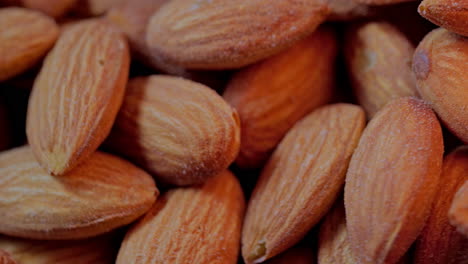 Top-closeup-view-of-raw-salted-almonds-pile-rotating-with-fire-abstract-background