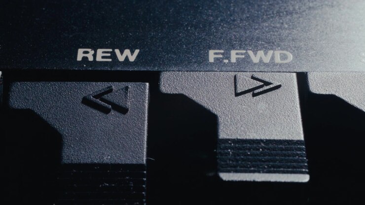 Macro di un dito che preme il tasto riavvolgi su un deck audio nero retrò