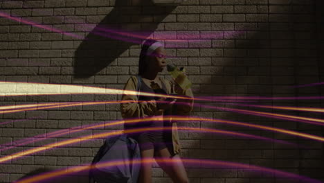 Woman drinking water and checking fitness app on phone against brick wall, showing animated streaks