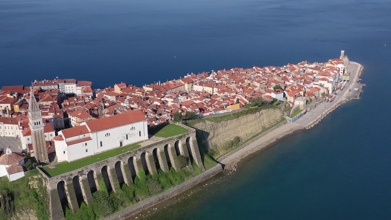 High aerial pull back drone view of parish of Piran and coastal village of red roofs, Slovenia