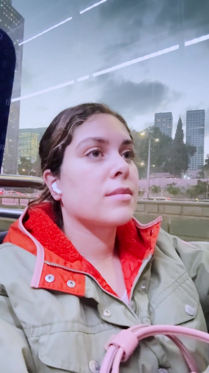 Giovane donna che ascolta musica viaggiando in autobus