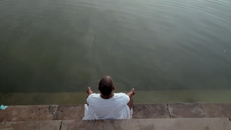 a man is sitting on the edge of a river with his feet in the water